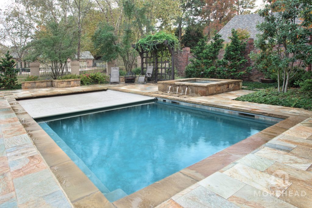 Elegant plunge pool with a built-in spa, natural stone deck, and lush garden surroundings.