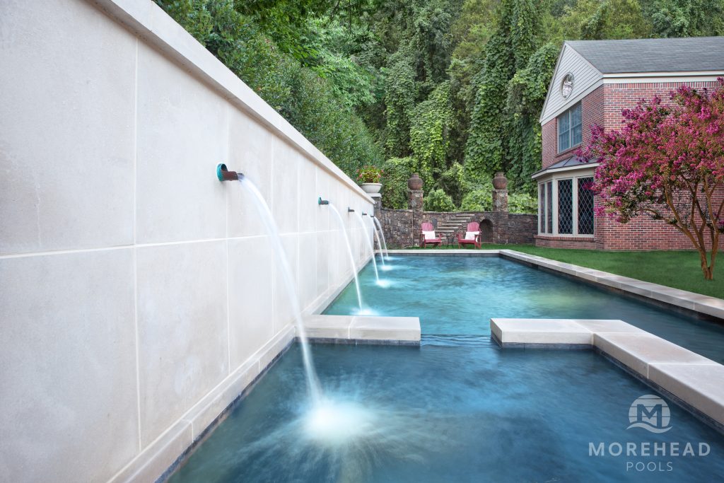 Luxurious backyard pool with cascading water features, modern design, and a scenic outdoor setting. 